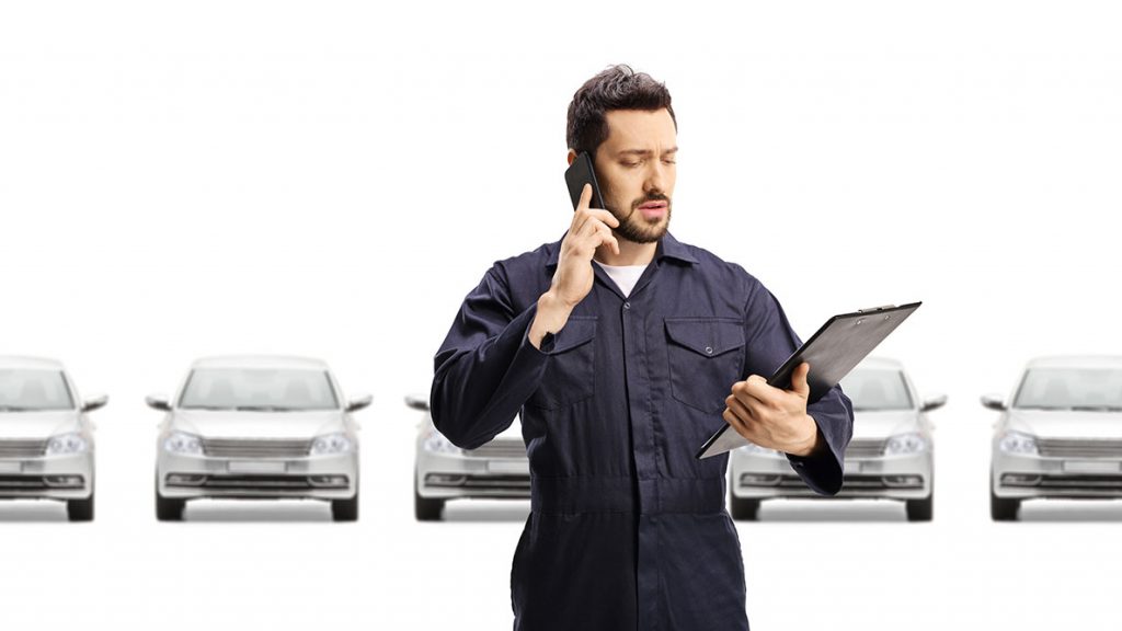 Perplexed man with clipboard in front of parked cars