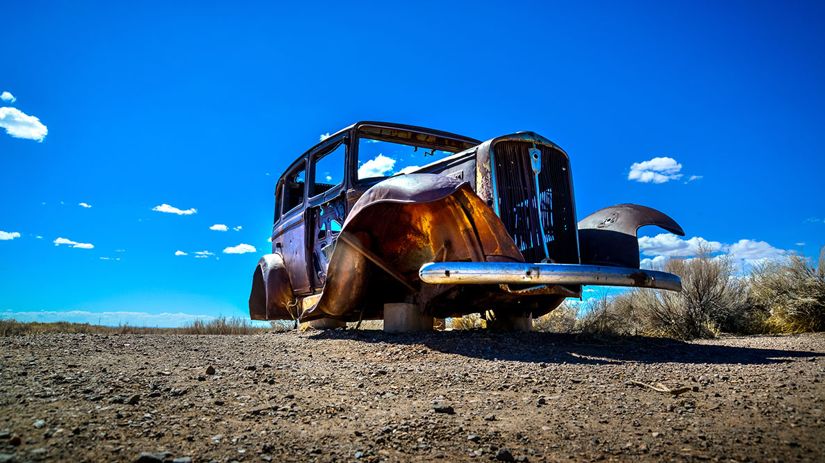 Old striped down car on desert ground
